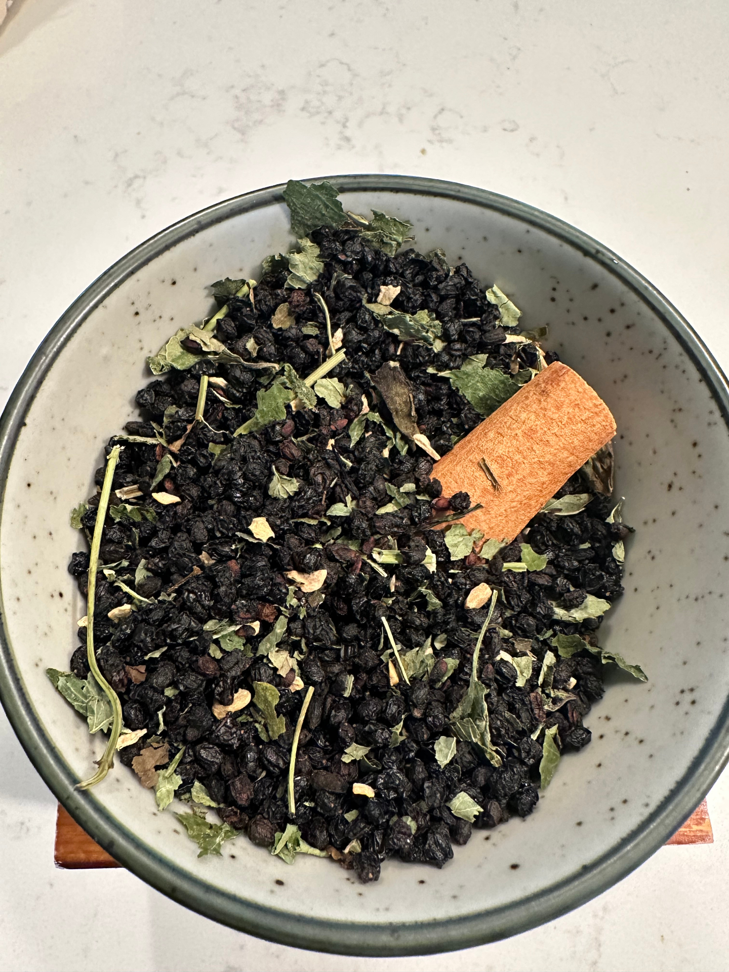 Elderberry + Lemon Balm botanical tea blend in a ceramic bowl